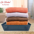 Go Hooked grey plastic storage basket filled with a stack of folded sweaters in orange, light purple, and brown.