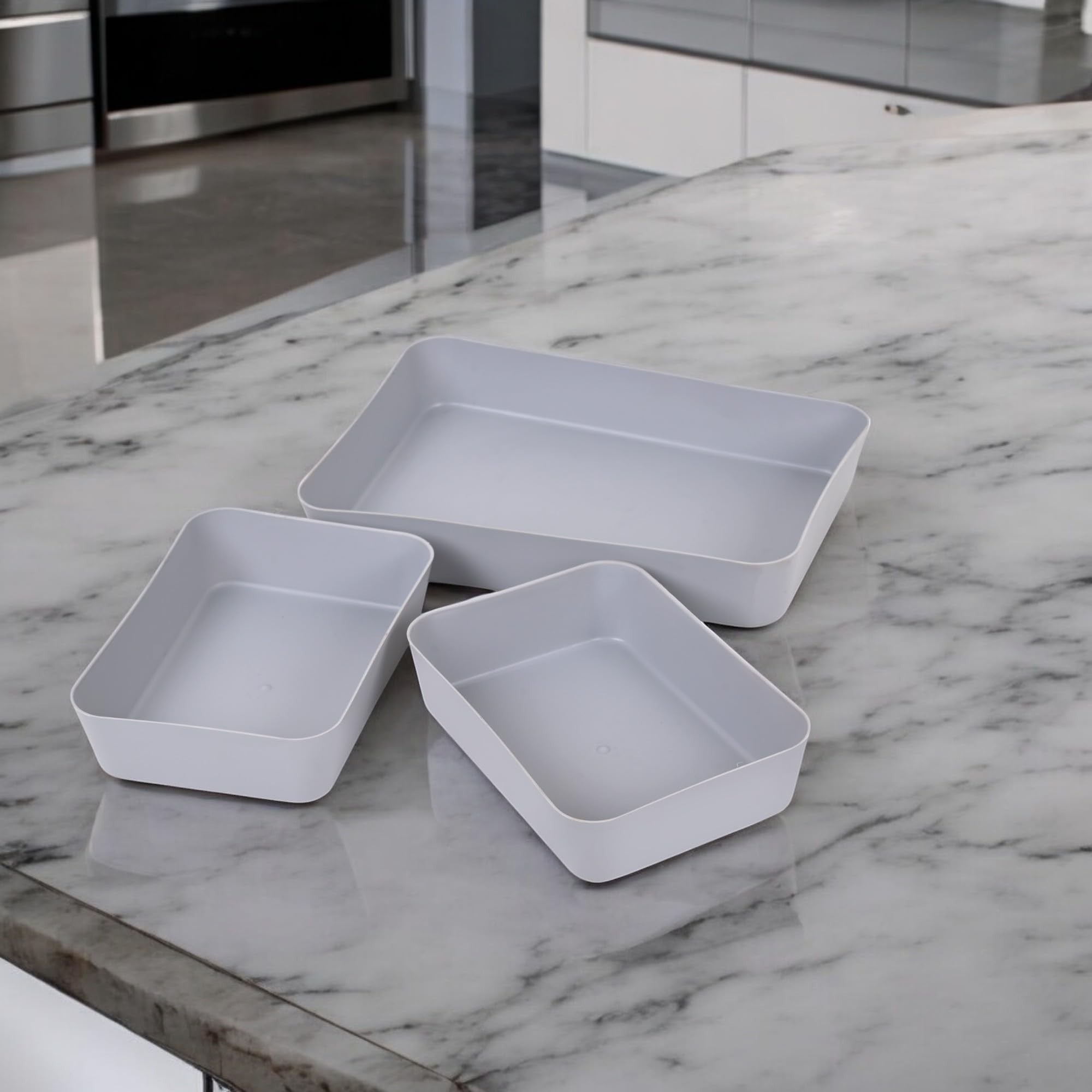 Go Hooked set of 3 grey plastic storage trays on a marble countertop. Versatile organizers for kitchen, office, makeup, and stationery.