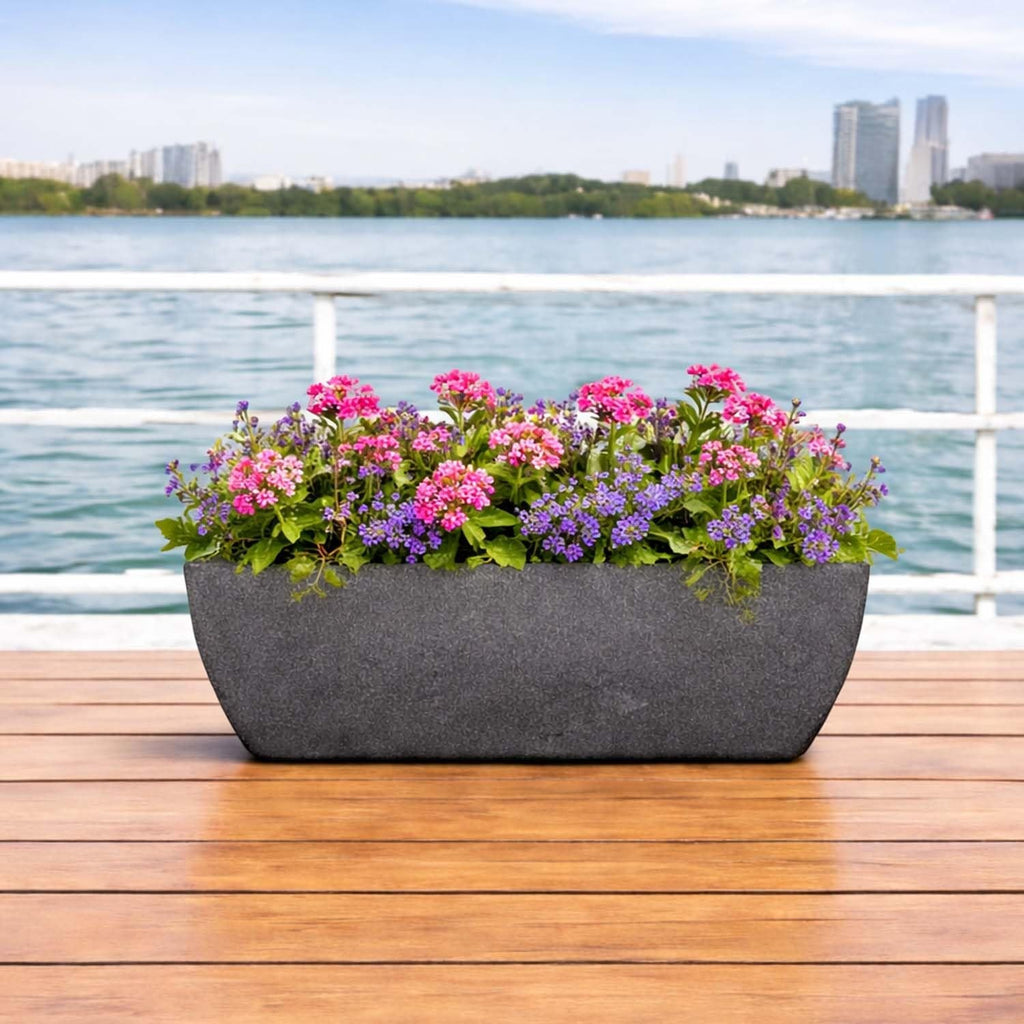 GoHooked grey rectangular polymer planter with ribbed design, filled with pink and purple flowers, on a wooden deck.