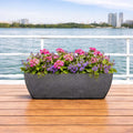 GoHooked grey rectangular polymer planter with ribbed design, filled with pink and purple flowers, on a wooden deck.