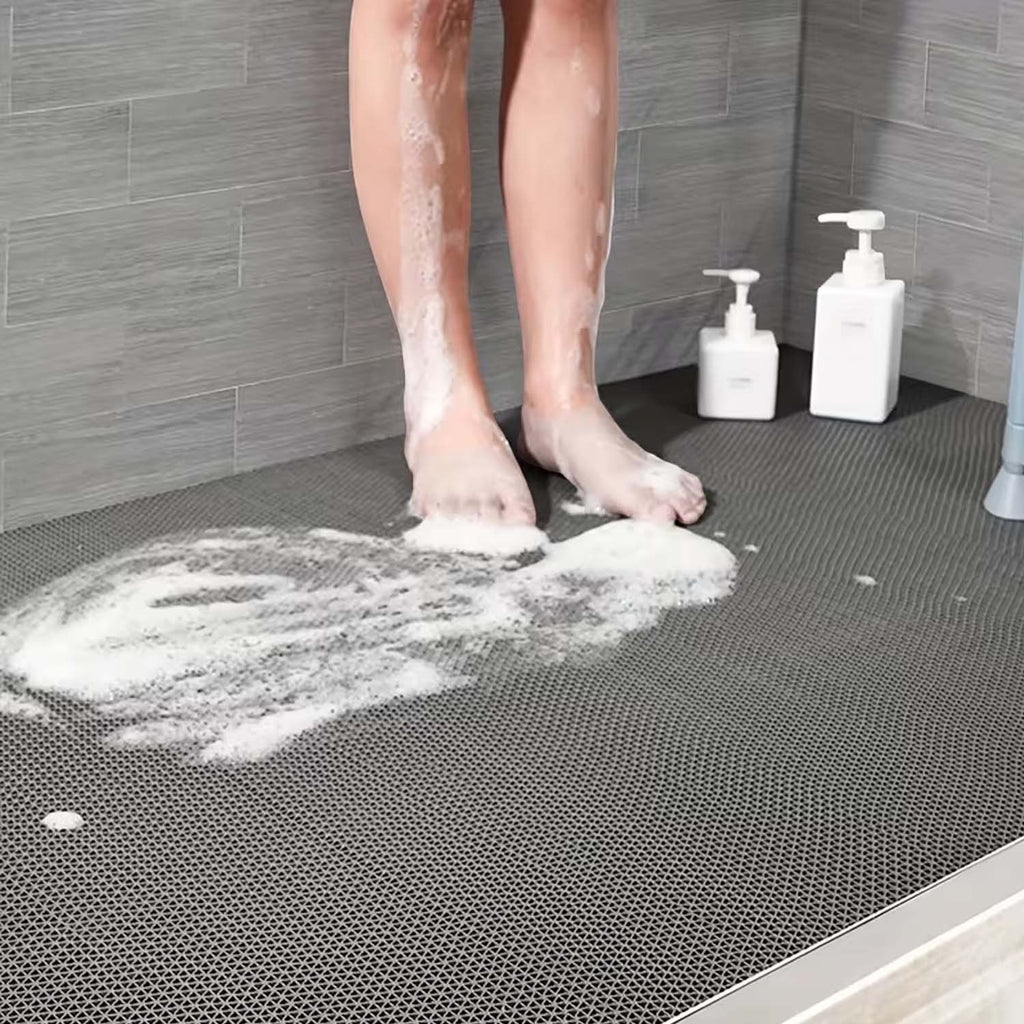 GoHooked grey rubber anti-skid bathroom mat with triangular drainage pattern in a shower stall with soapy water.