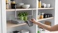GoHooked grey 12-inch steel undershelf basket with white wire frame, holding folded striped towels and green potted herbs.