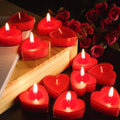 GoHooked red heart-shaped wax candles with lit wicks, arranged on a wooden surface with red roses in the background.