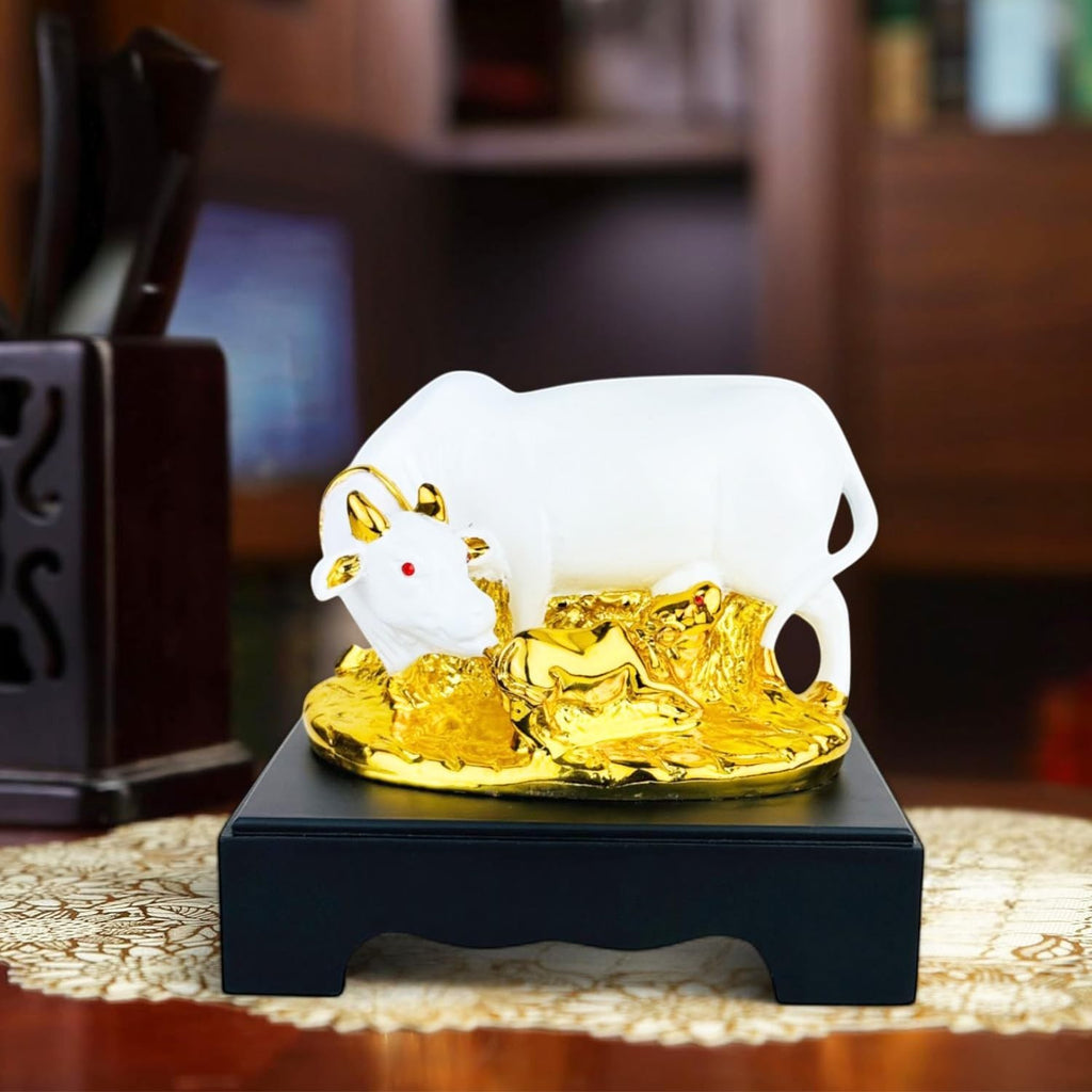 Go Hooked white polyresin Kamdhenu cow and calf statue with gold accents and red eyes on a black base.