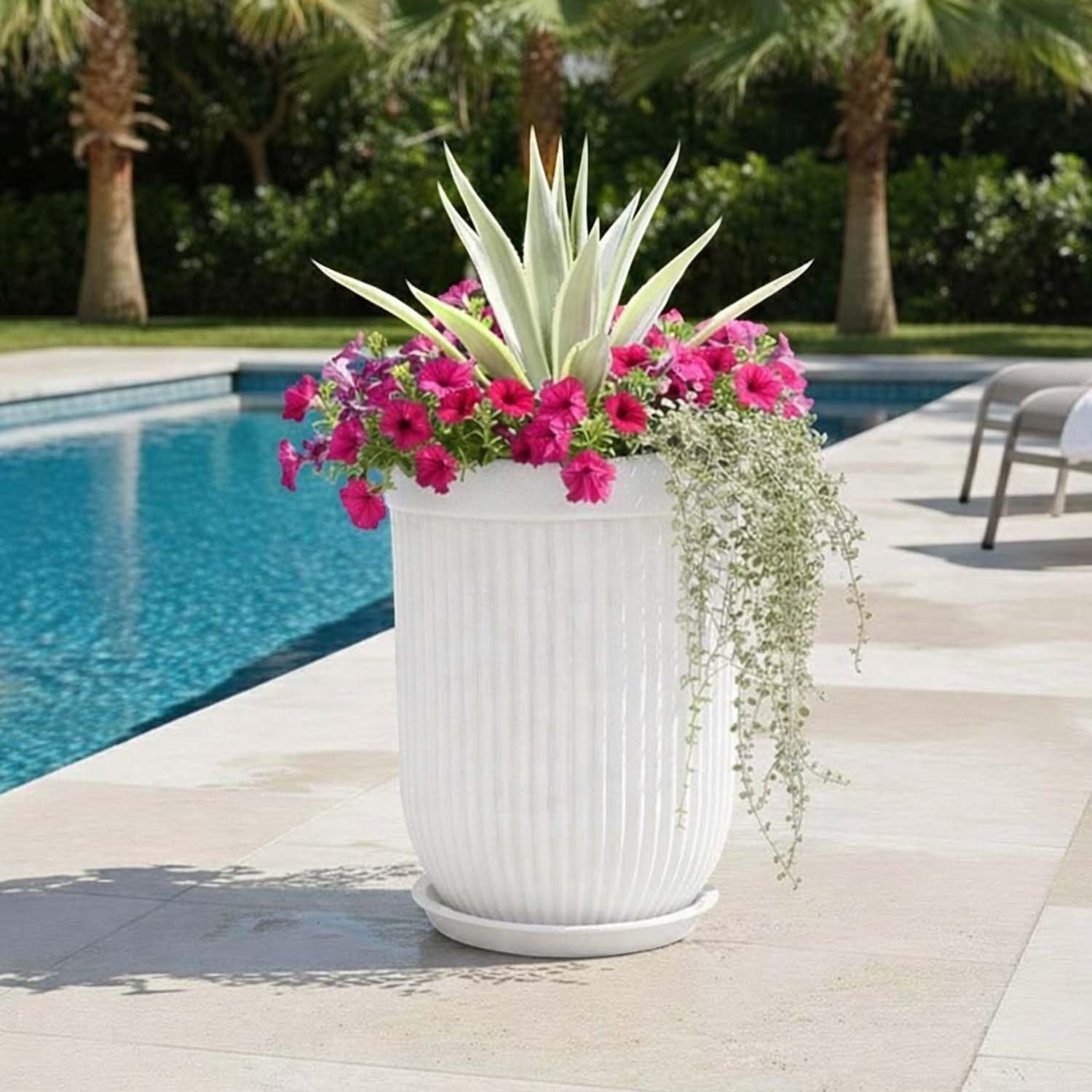 GoHooked large white ribbed polymer planter with pink flowers and trailing plants by a pool.