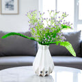 Go Hooked lavender baby's breath artificial flowers with green fern leaves in a white geometric vase.
