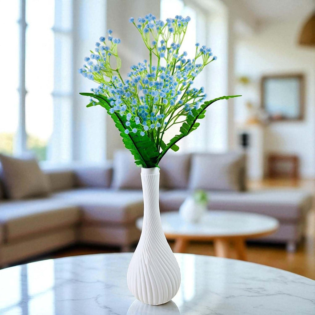 GoHooked light blue artificial baby's breath flowers with fern leaves in a white surahi vase on a marble table.