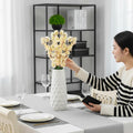 GoHooked light yellow artificial flowers in a white textured vase on a dining table.