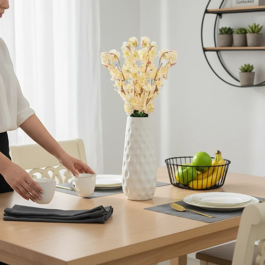 GoHooked light yellow artificial flowers in a white textured vase on a dining table.