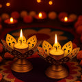 GoHooked set of 2 matte-gold metal lotus tealight holders with lit candles, intricate petal design.