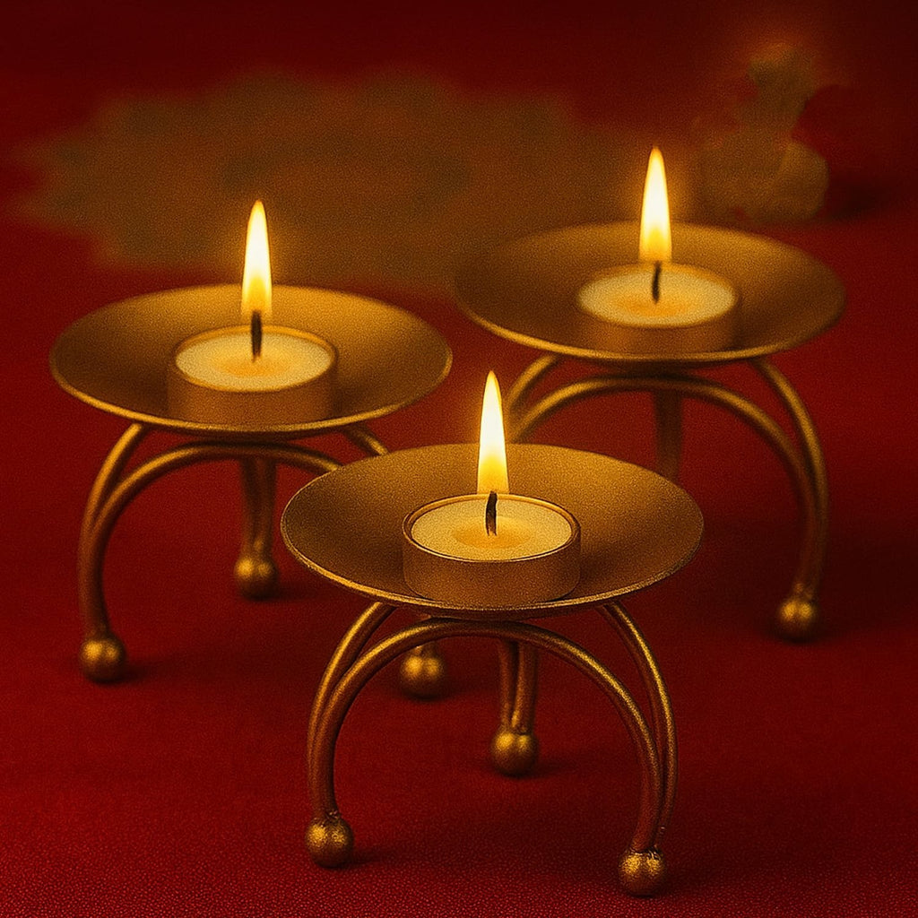 Go Hooked set of 3 matte gold metal pedestal candle holders with lit tealights on a red surface.