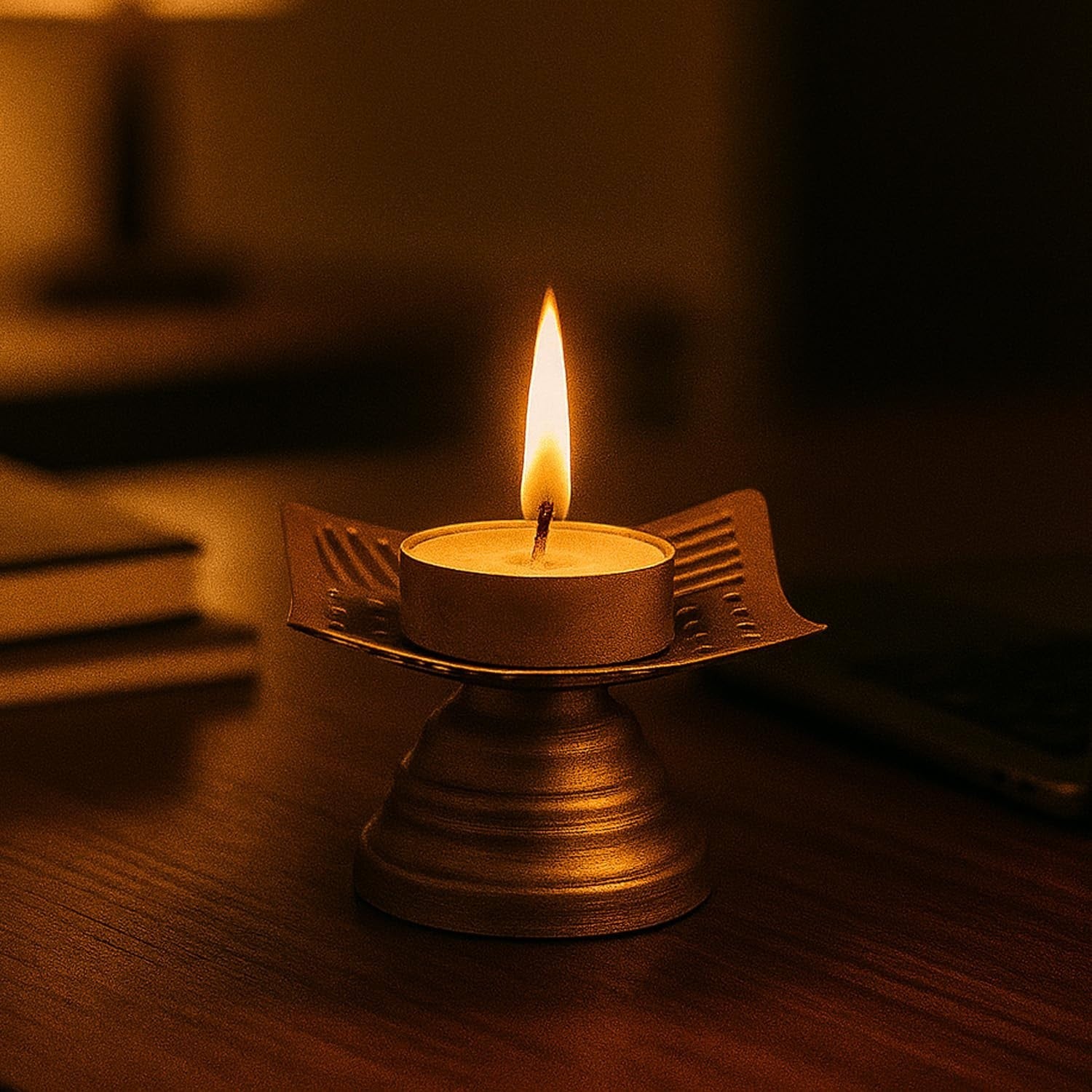 Go Hooked matte gold metal tealight candle holder with floral cutouts and a lit candle.