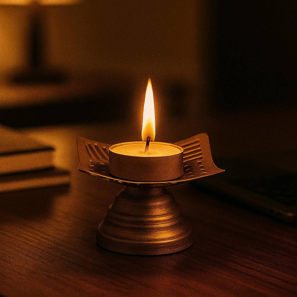 Go Hooked matte gold metal tealight candle holder with floral cutouts and a lit candle.
