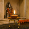 GoHooked matte gold metal pedestal diya stand with a lit candle, set of 4, ideal for Diwali and home decor.
