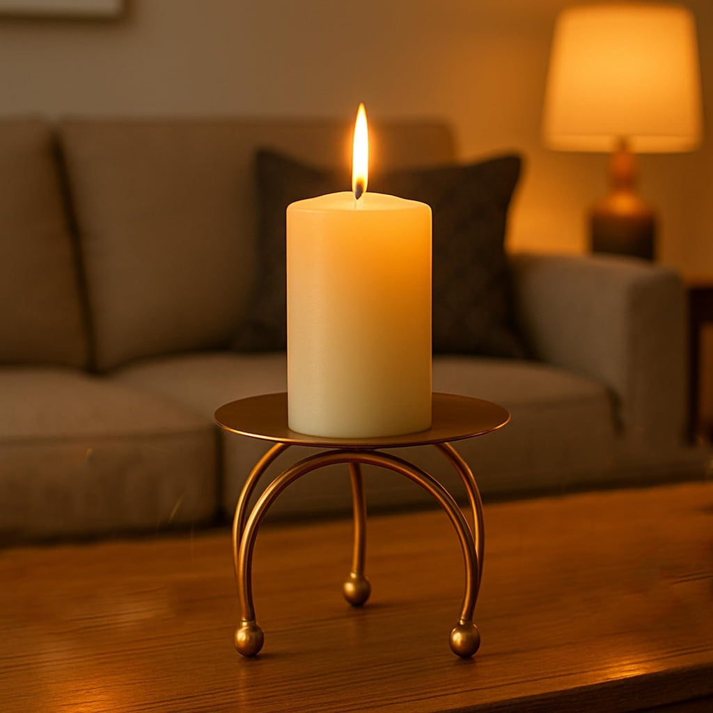 GoHooked matte gold metal pedestal stand with a cream pillar candle, featuring a tripod base and ball feet. Ideal for festive decor.