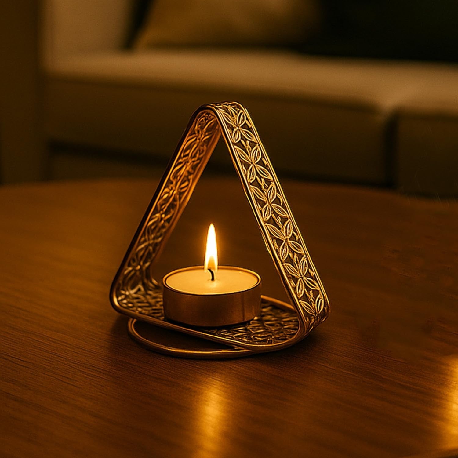 GoHooked matte gold metal triangle tealight holder with floral cutwork, holding a lit tealight candle.