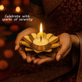 GoHooked matte gold metal flower tealight holder with a lit candle held in hands.