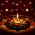 GoHooked handcrafted matte gold metal flower tealight holder with a lit candle, surrounded by orange and yellow flowers.