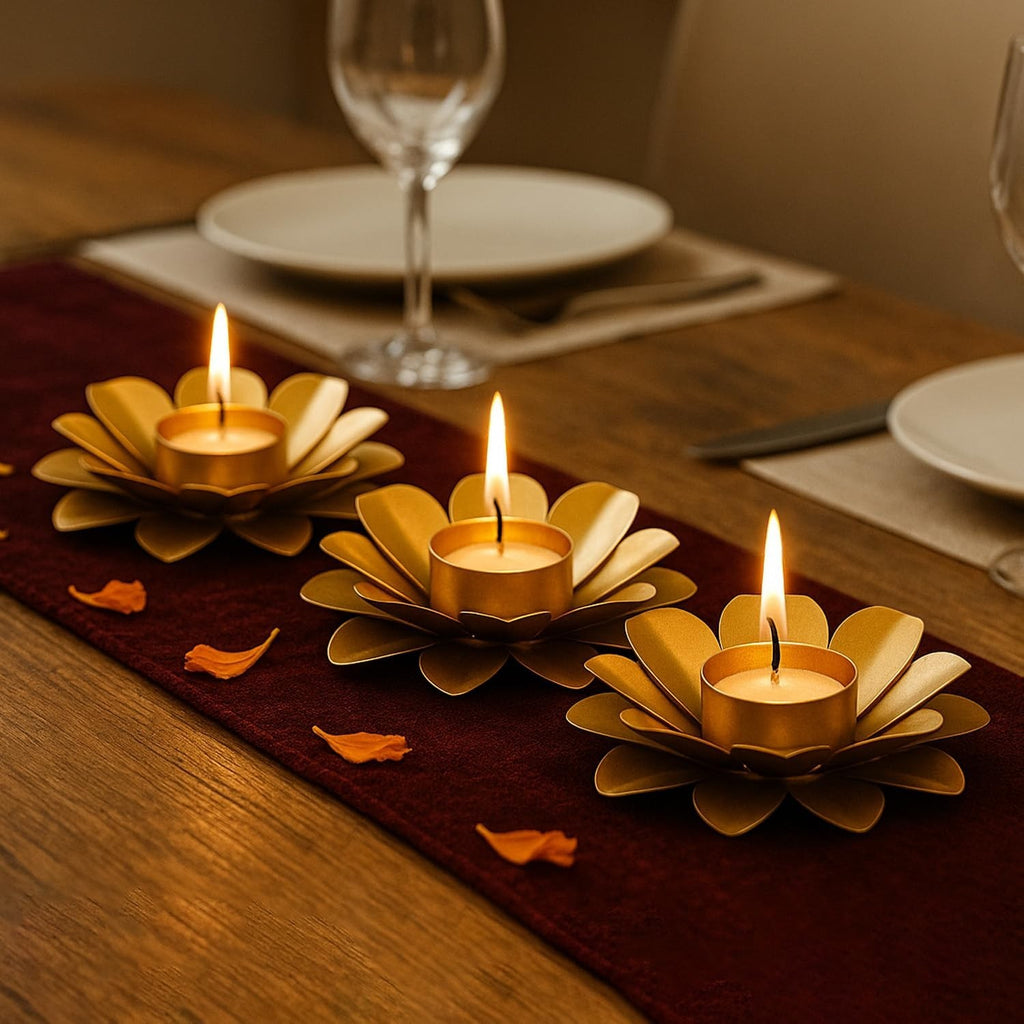 GoHooked set of 3 matte gold metal lotus tealight holders with lit candles on a table runner.