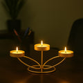 Go Hooked matte gold metal tabletop tealight candle holder with three lit candles, 25cm decorative iron stand