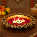 Go Hooked decorative metal urli bowl with rose accents, holding four lit tealights and red rose petals.