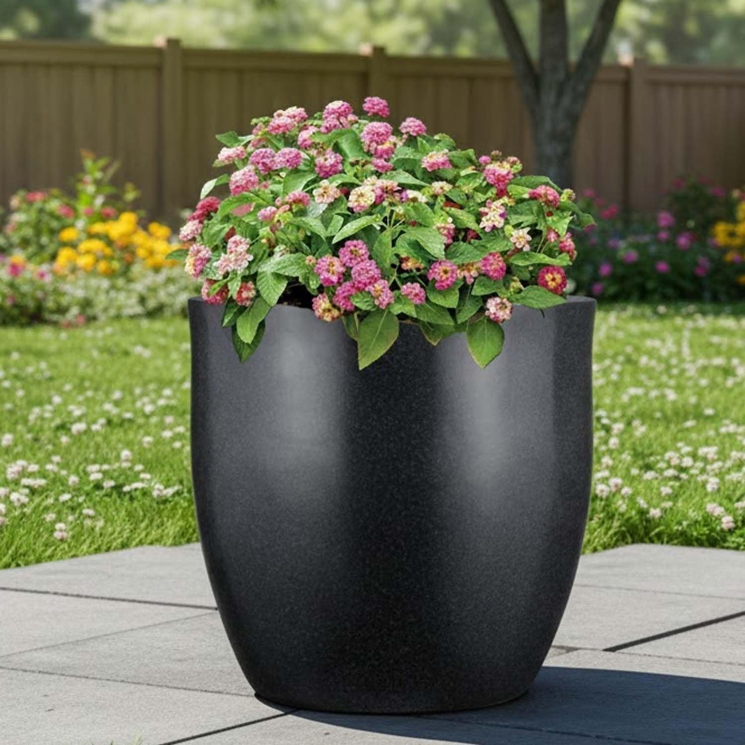 Go Hooked 20 inch modern round black polymer planter with pink flowers, perfect for indoor or outdoor use.