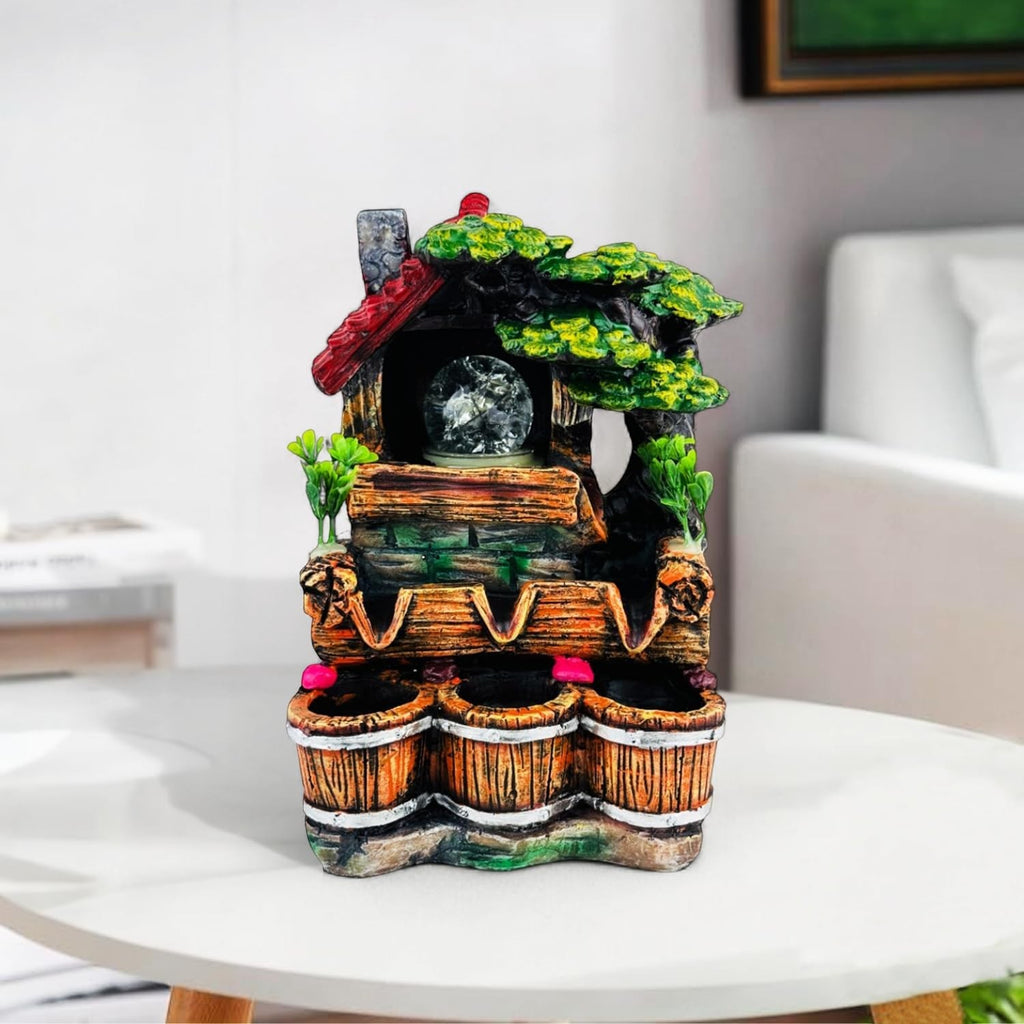 Go Hooked multicolor polyresin tabletop waterfall fountain with LED light and adjustable speed control, featuring a house and tree design.