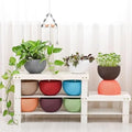 Go Hooked multicolor rattan woven plastic hanging planters with plants on a white shelf unit.