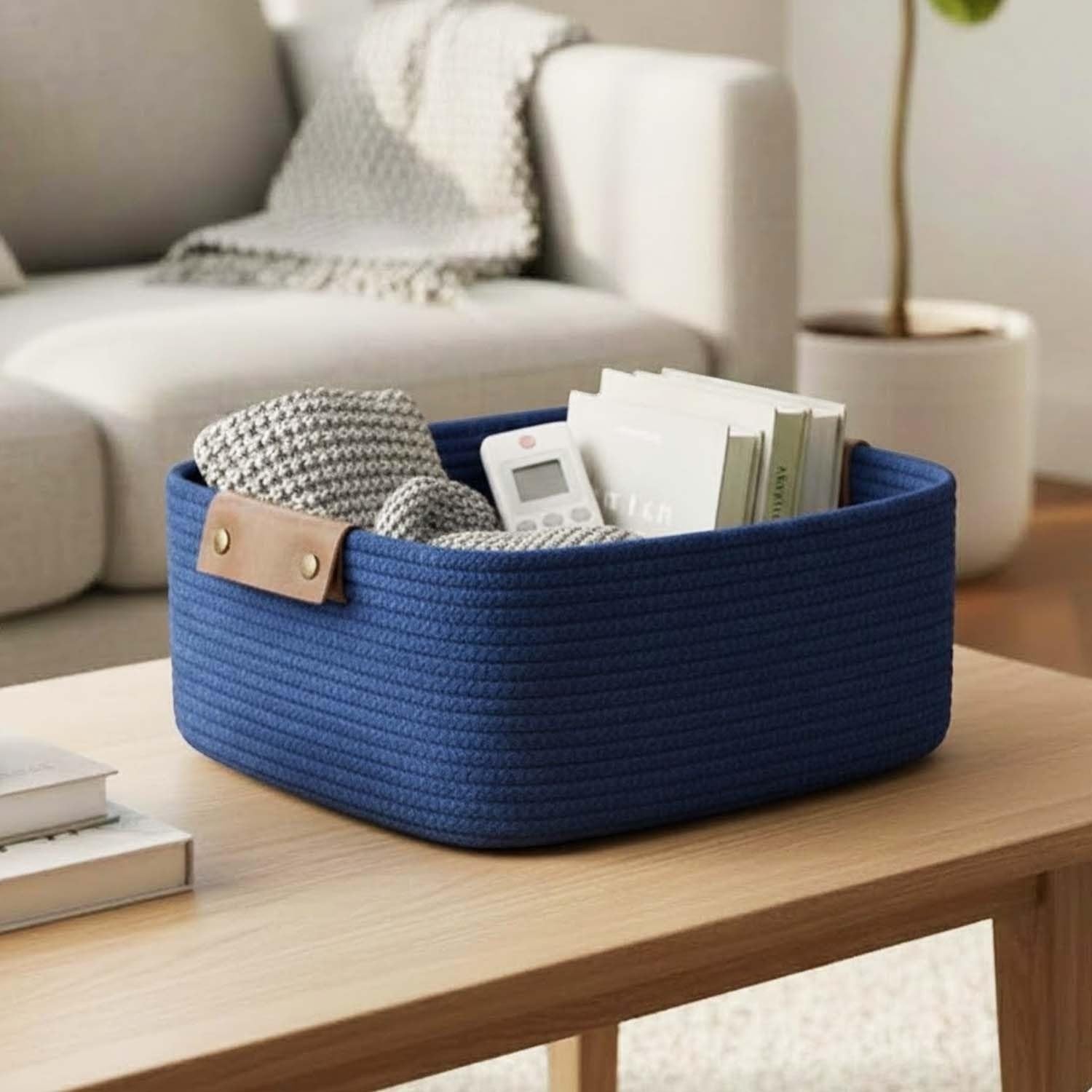 GoHooked rectangular navy blue cotton rope storage basket with brown PU leather handles, holding blankets and books.