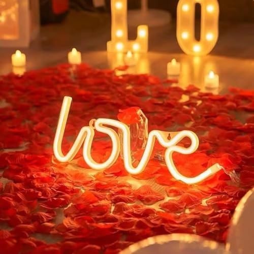GoHooked white neon "love" sign surrounded by red artificial rose petals and LED candles.