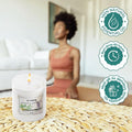 GoHooked ViMe Neroli & Patchouli scented candle in a white jar, burning with a woman meditating in the background.
