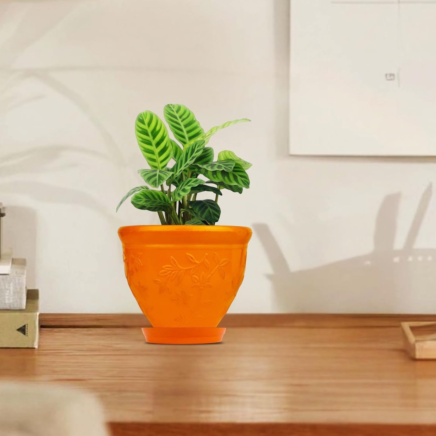 GoHooked orange plastic planter pot with embossed floral design and matching saucer, holding a green plant.