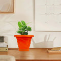 GoHooked orange plastic planter pot with saucer, featuring a modern twister design and drainage holes, perfect for indoor or outdoor plants.