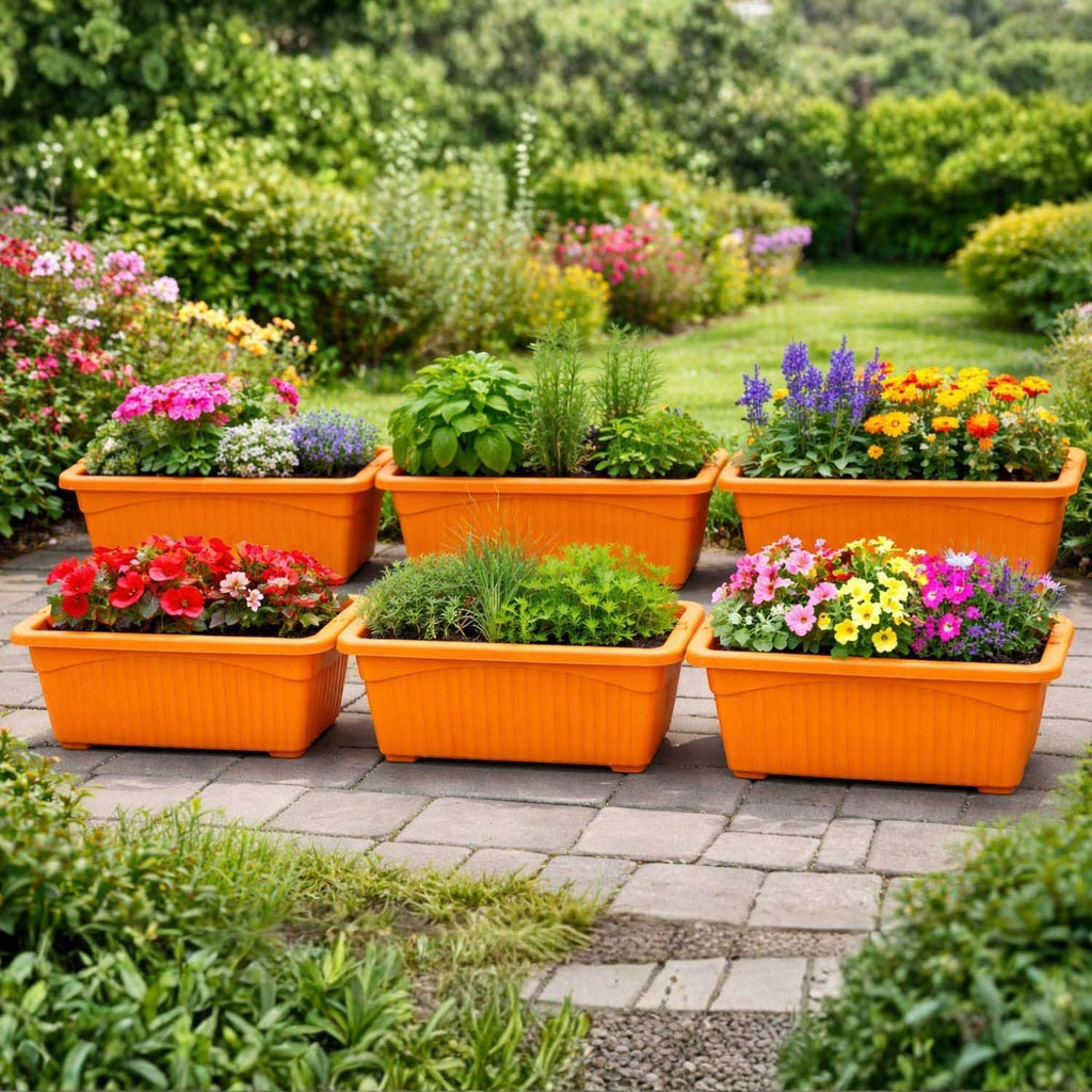 Go Hooked set of 6 orange rectangular plastic planters filled with colorful flowers and greenery, arranged on a stone patio.