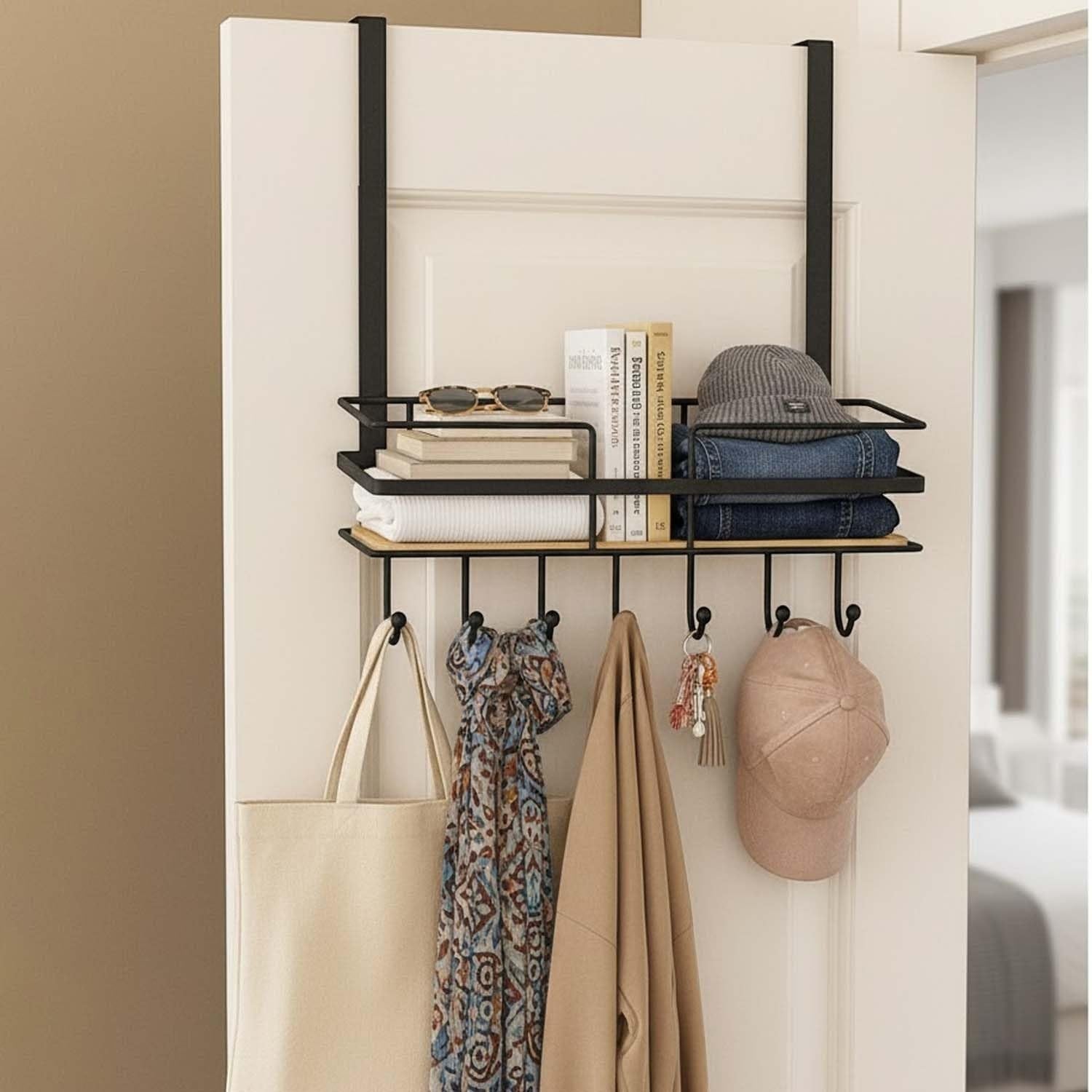GoHooked black metal over-the-door organizer with shelf and hooks, holding books, sunglasses, hat, jeans, scarf, bag, coat, and keys.