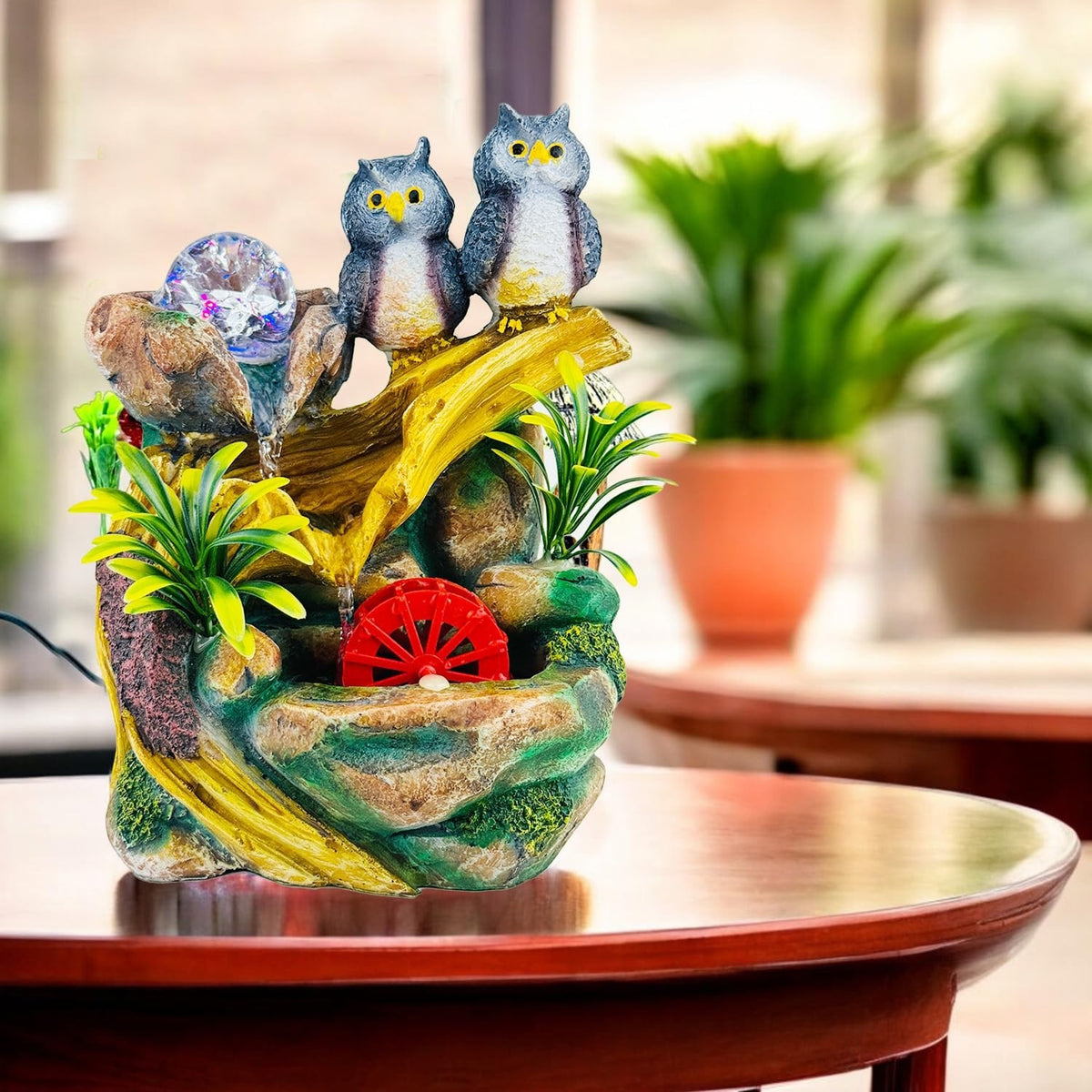 Go Hooked polyresin tabletop fountain with two owls, LED lights, and a red water wheel. Multicolour.