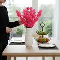 GoHooked pink artificial flowers in a textured white ceramic vase on a dining table.