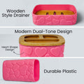 Go Hooked pink plastic bathroom accessory set with heart embossed design, featuring a soap dish with wooden style drainer and a toothbrush holder with dual-tone lid.