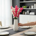 Go Hooked pink and white artificial flowers in a textured white vase on a dining table.