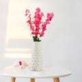 GoHooked pink and white artificial flowers in a textured white ceramic vase, with two loose flowers on the side.