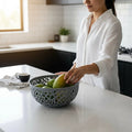 Go Hooked light grey plastic fruit bowl with intricate cutout design, holding mangoes on a kitchen counter.