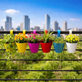 GoHooked colorful plastic hanging lily pots with plants on a balcony railing, city skyline background.
