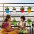 Go Hooked assorted color plastic lily hanging pots, 6-inch, pack of 4, with a woman and child gardening on a balcony.