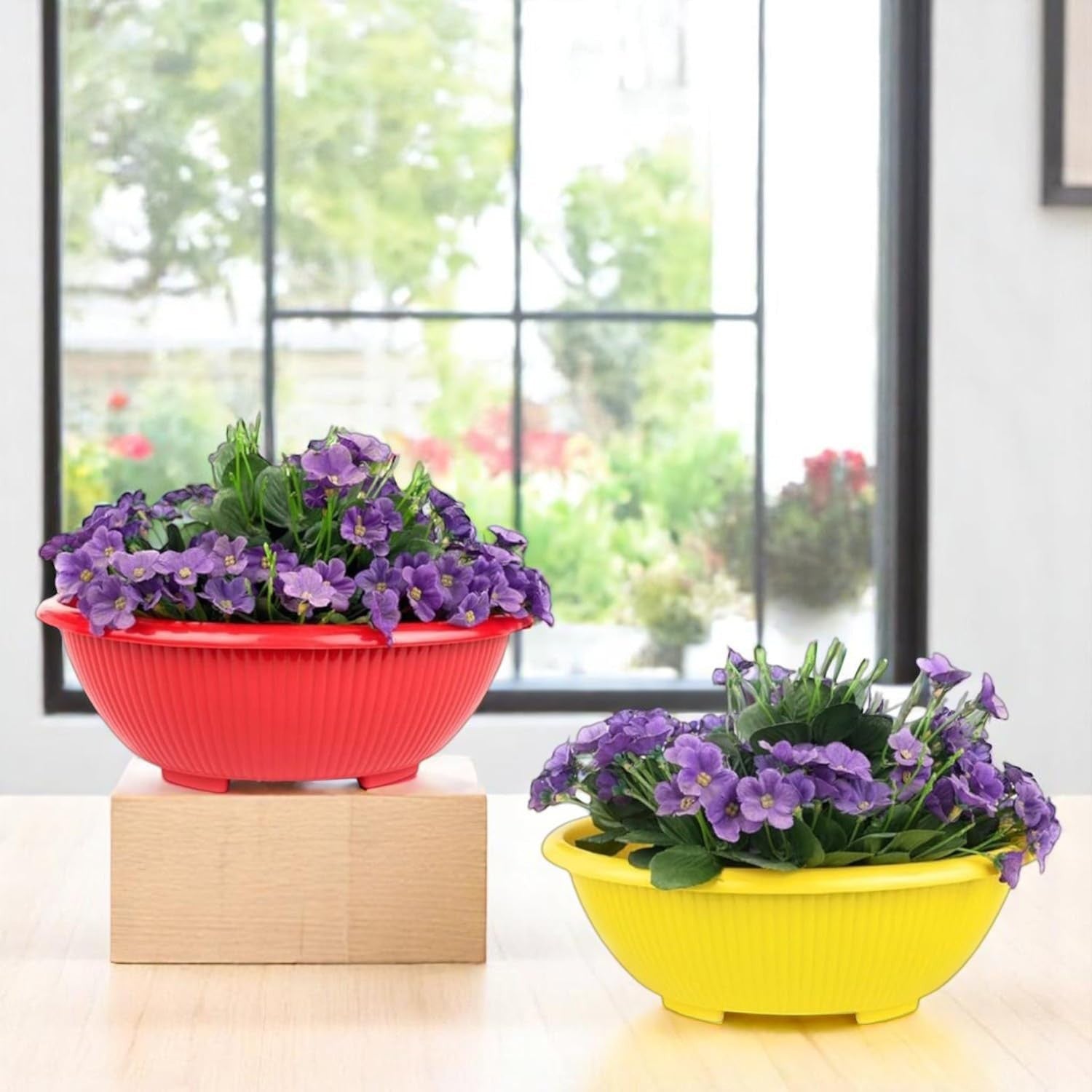 GoHooked set of 3 multicolor plastic planter pots with purple flowers. Red and yellow bowls on a table.