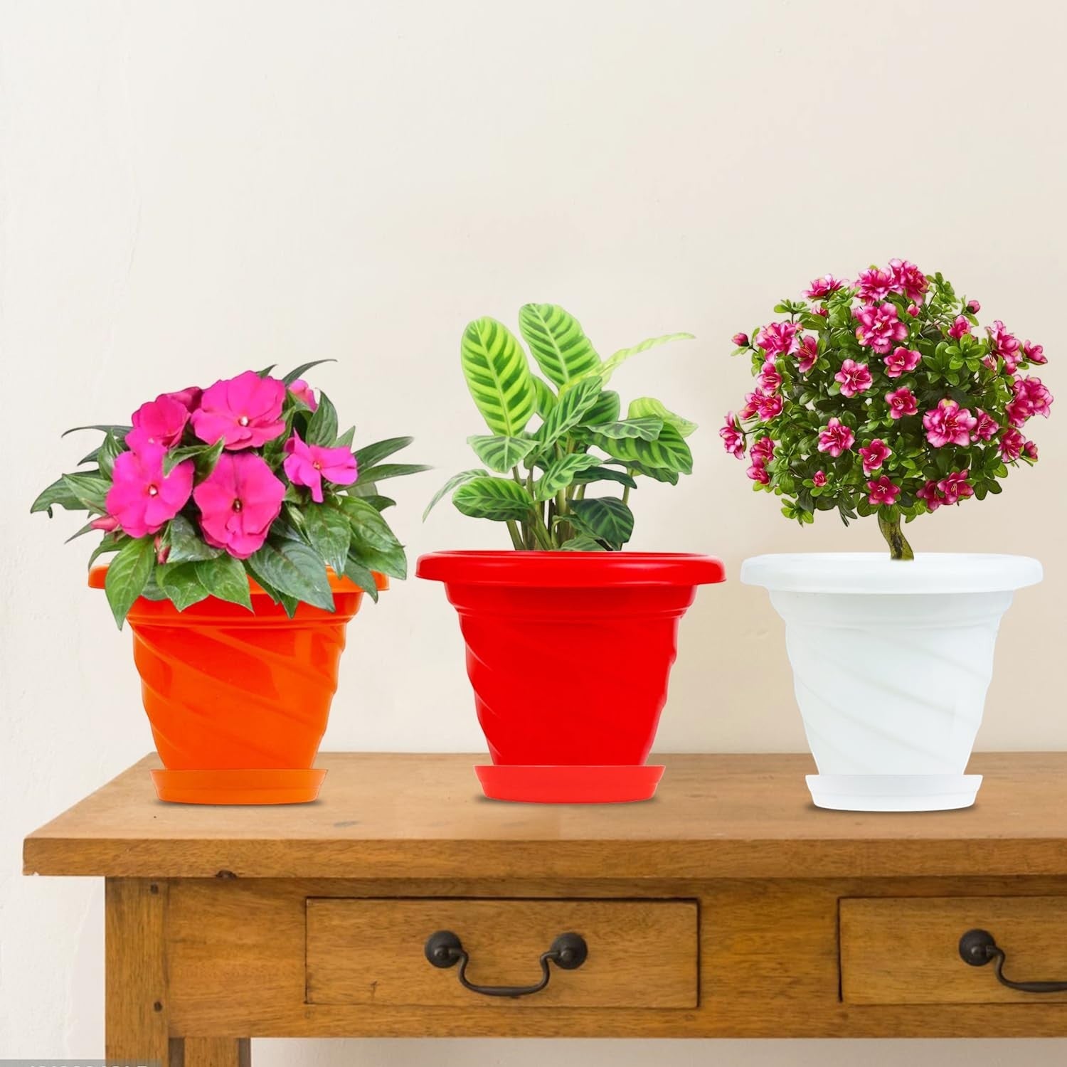 Go Hooked set of 3 multicolor plastic planters with saucers. Orange, red, and white pots with plants.