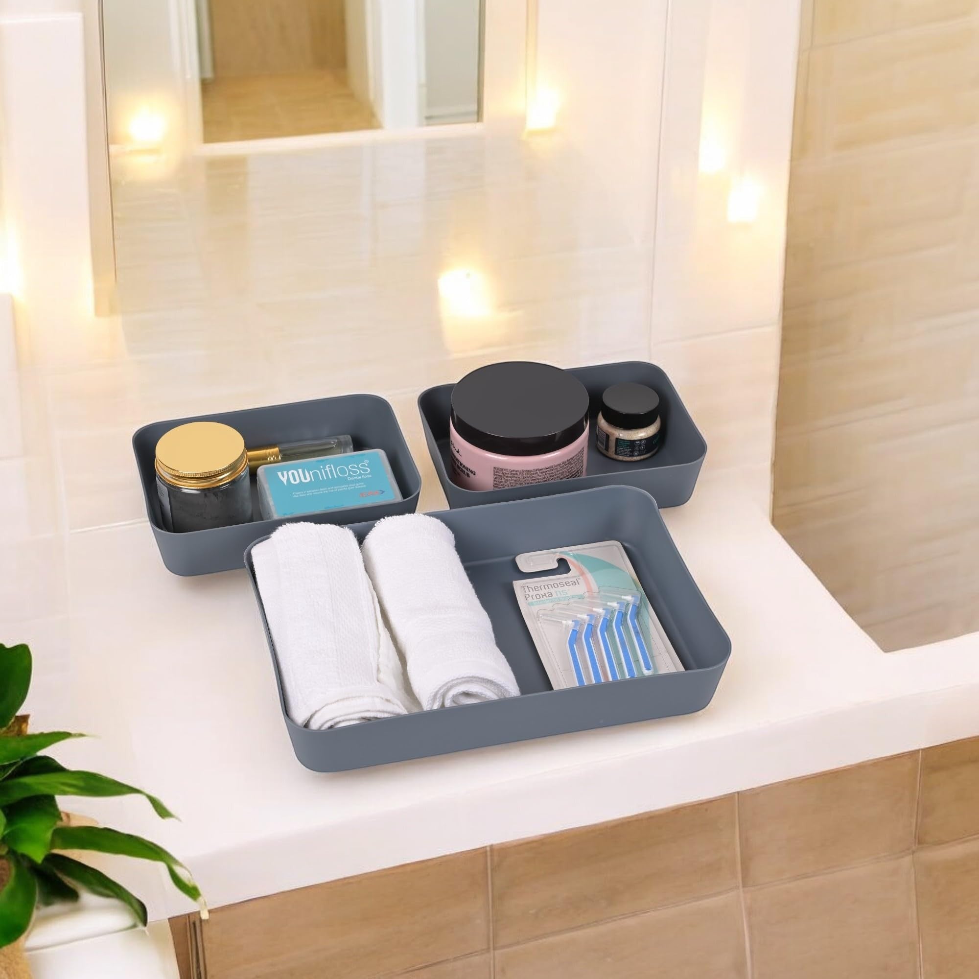 GoHooked set of 3 dark grey plastic storage trays organizing bathroom essentials like floss, towels, and razors.