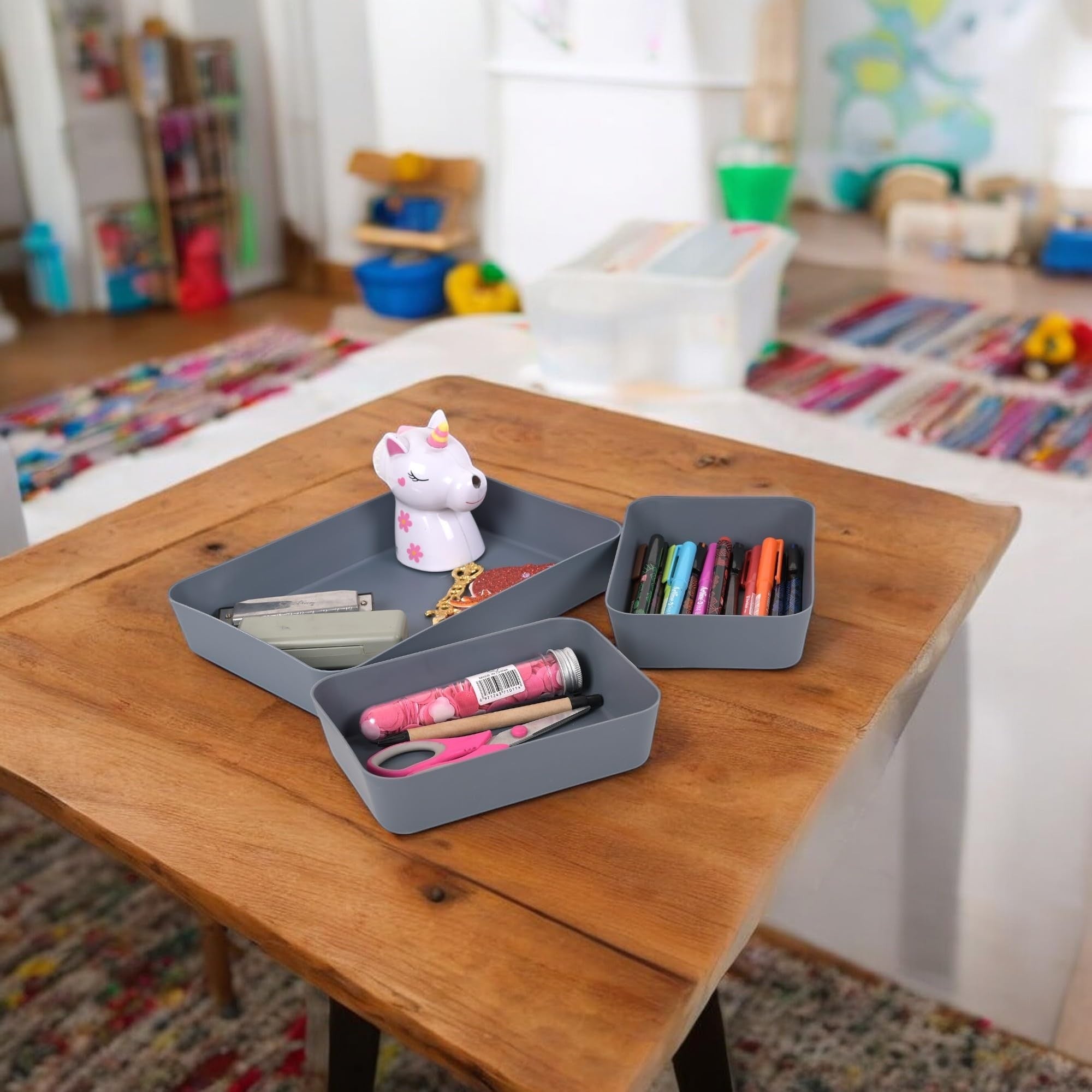 Go Hooked set of 3 dark grey plastic storage trays, one with a unicorn, stapler, and glitter; another with pens; and the third with scissors and a tube of confetti.