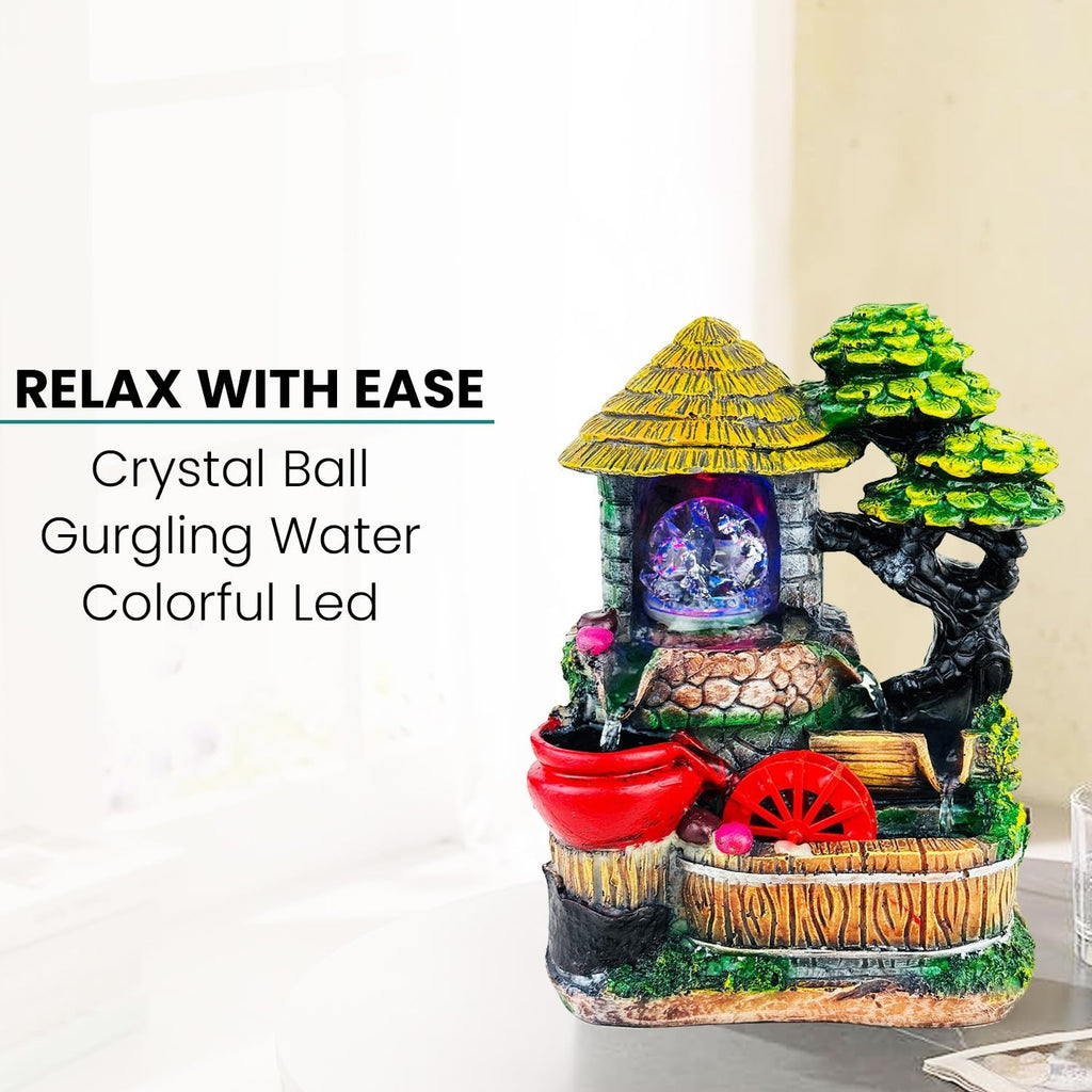 Go Hooked polyresin tabletop waterfall fountain with crystal ball, colorful LED lights, and adjustable water flow. Features a rustic house and tree design.