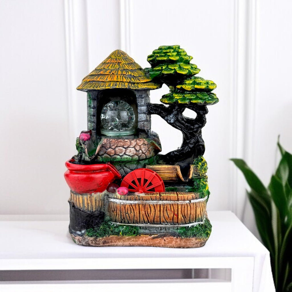 Go Hooked polyresin tabletop fountain with a thatched roof well, red pot, water wheel, and LED lights. Multicolour.