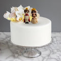 GoHooked Prince and Princess couple figurines with crowns, on a white cake with floral decorations.